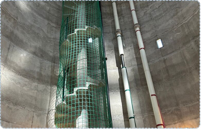 Filet de protection vert installé autour d'une colonne dans un ouvrage béton