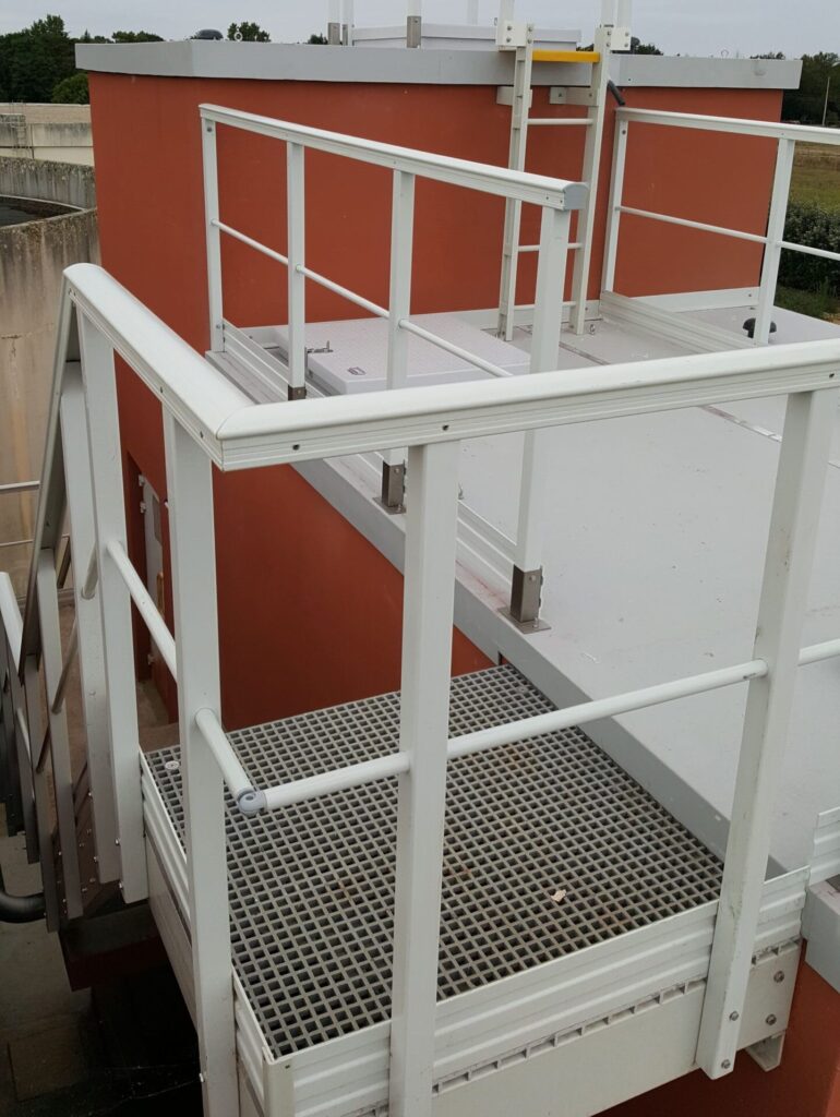 Garde-corps PRV blanc devant un bâtiment technique à façade ocre