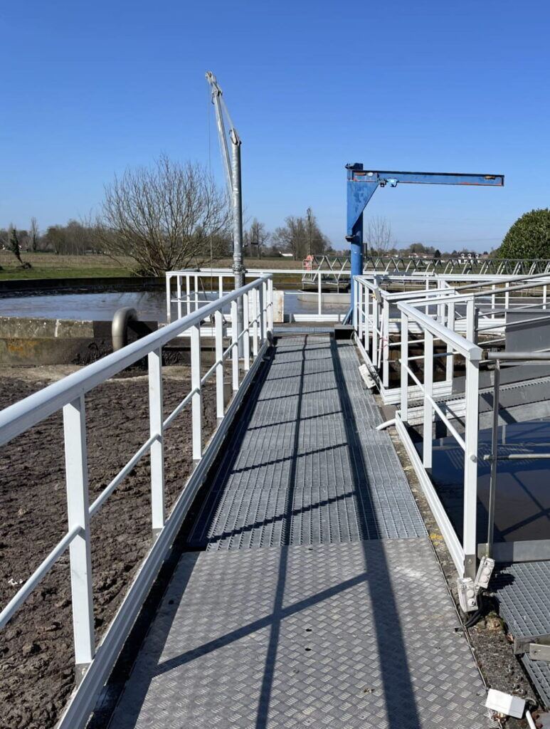Passerelle PRV avec garde-corps blanc au-dessus d'un bassin de traitement