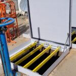 Trappe PRV ouverte en local technique, barreaux antichute jaunes et tuyauterie orange
