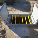 Trappe PRV blanche ouverte sur dalle béton, barreaux antichute jaunes visibles